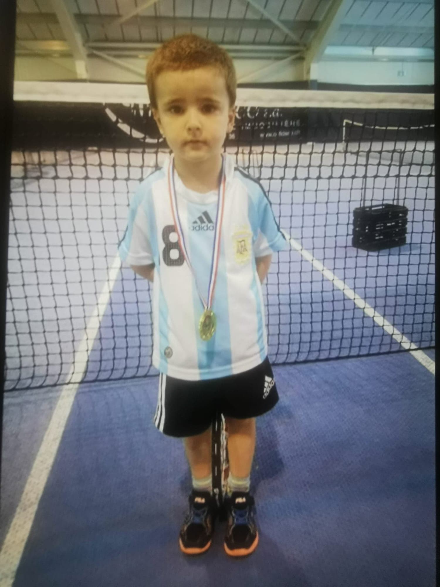 Lenart à 4 ans, raquette et médaille autour du cou, sur un court de Vevey